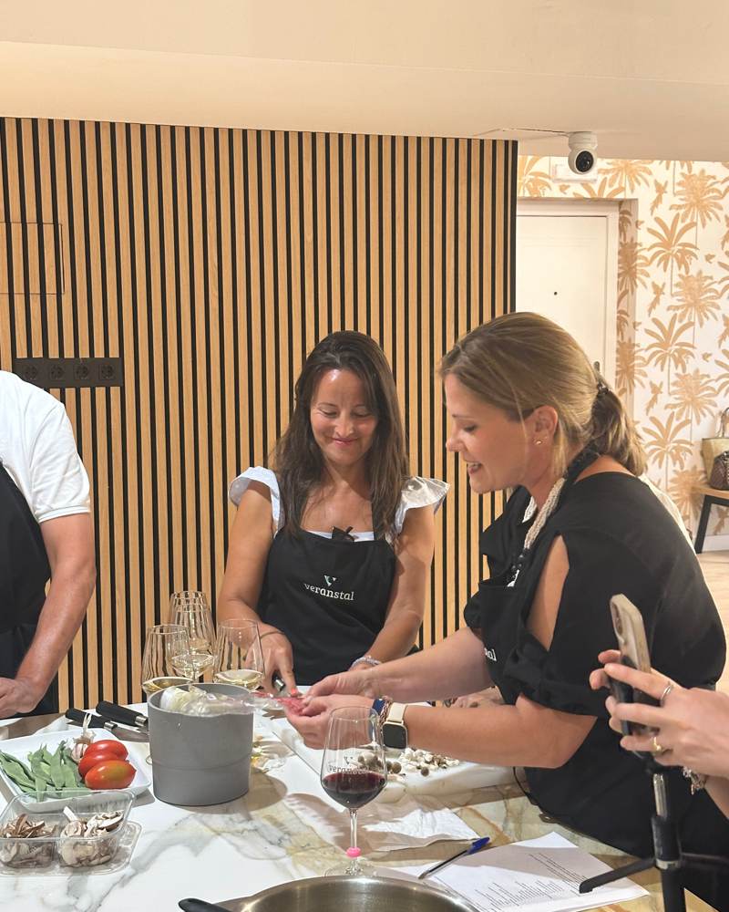 Dos participantes cocinando y riéndose en la isla